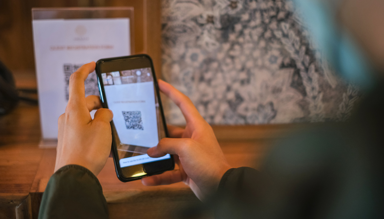 A phone scanning a QR code sign at an event check-in counter